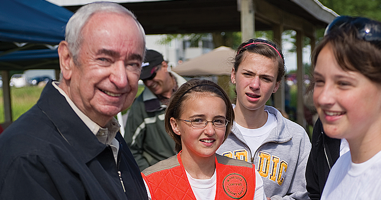 A man wearing a black jacket with cmpetitors.